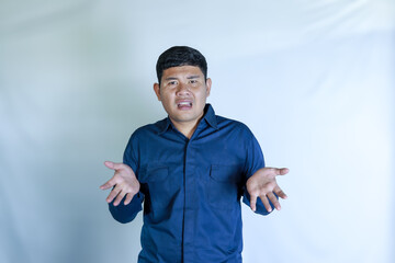 young asian man in blue shirt with confused expression with hand gesture, his face shows pain expression, headache with white studio background. Concept of disease, treatment, health care