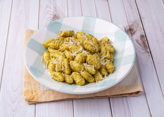 Italian pasta gnocchi on a plate with pesto sauce and parmesan cheese