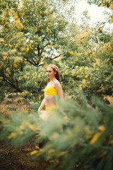 Girl in a yellow swimsuit in a February mimosa garden