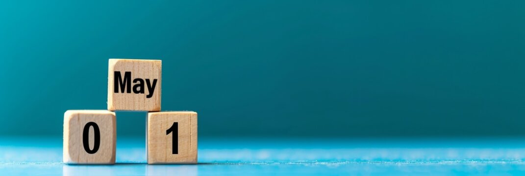 Wooden blocks displaying May 01 against a vibrant blue background, symbolizing the start of a new month.