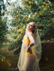 Girl in a yellow swimsuit in a February mimosa garden