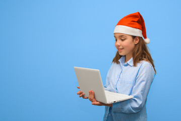 Teenager in Santa hat with laptop. Christmas online. Copy space