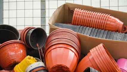 Multi-colored plastic planters are stacked in piles inside the greenhouse.