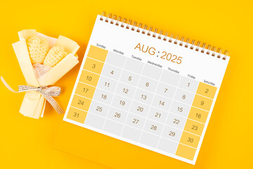 August 2025 desk calendar with bouquet flower on yellow background.