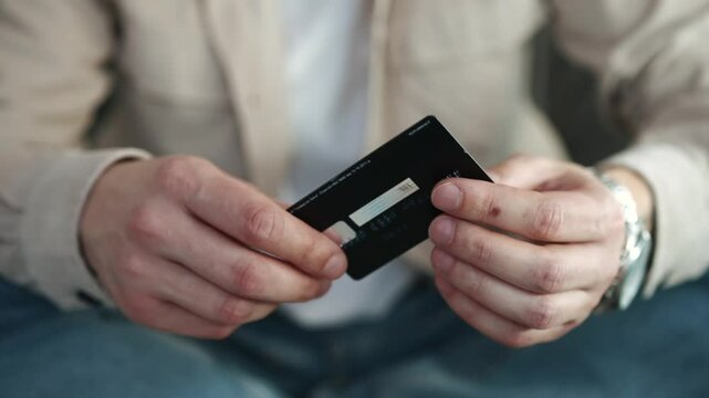 Cashless payment by bank card. A man with a bank card and a phone in his hands. Online shopping via the Internet. Payment by card. Shopping, online, card, bank, money