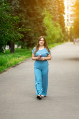 A woman walking with coffee in a sunny park, surrounded by lush greenery. Perfect for lifestyle, outdoor relaxation, and nature enjoyment themes.