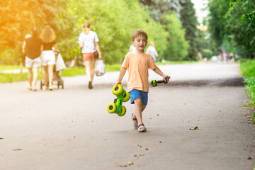 A cheerful child plays with a remote-controlled car on a sunny day in the park. His joyful expression and summer outfit highlight the fun moment.