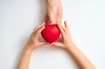 International Children's Day adult and child hands gently holding bright red heart symbolizing care...