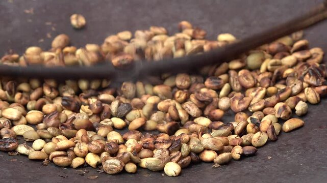 Close-up of fresh coffee beans being roasted on fire wood stove in tribal village of Dorze, traditions and culture in Ethiopia
