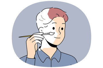 Self-sufficient man artist paints own face and hair with brush, creating self-portrait. Self-sufficient guy draws look, for concept of independence and personal improvements thanks to fortitude