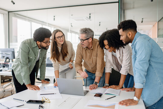 Multicultural business team discussing ideas in a modern office. A diverse group of professionals collaborating on a project, brainstorming strategies, and working together at a desk with documents