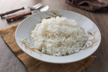 Cooked white rice or steamed rice in a ceramic plate with rice pattern screen with spoon and fork and eggs, thai jasmine rice, thai fragrant rice, 