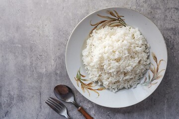Cooked white rice or steamed rice in a ceramic plate with rice pattern screen with spoon and fork , thai jasmine rice, thai fragrant rice, 