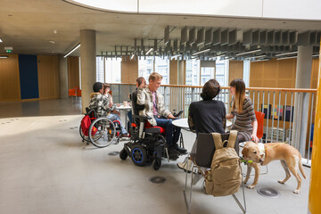 People with various disabilities at tables in hallway