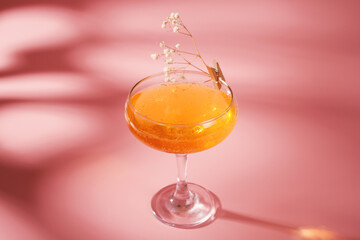 Glass with cocktail on pink background. Alcoholic cocktail