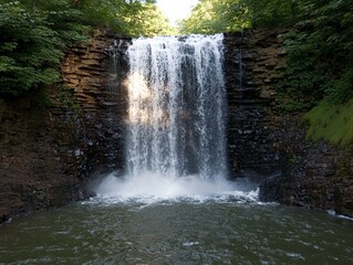 Obraz premium Majestic Waterfall Cascading Over Rocks Serene Forest Nature Photography Tranquil Environment Eye-Level Natural Beauty