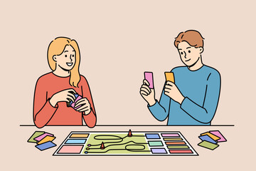Happy couple playing board game while spending free time together and having fun after working day. Positive men and girl compete in board game, allowing them to get closer and improve mood