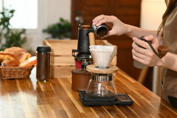 A woman is making coffee using a French press. She is pouring coffee grounds into the French press and adding water.