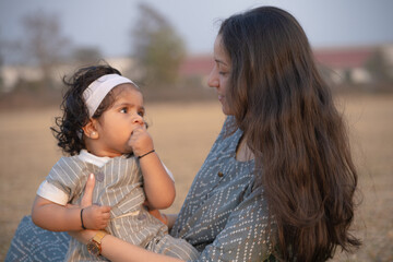 First Steps. Adorable smiling Indian mother walks with her infant son 
