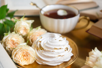 A cup of aromatic tea, a book and a rose on the table.