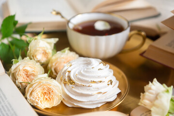A cup of aromatic tea, a book and a rose on the table.