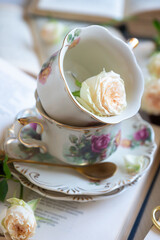 A cup of aromatic tea, a book and a rose on the table.