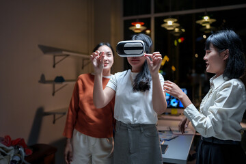 Asian businesswomen using virtual reality headset in modern office at night, exploring virtual reality, metaverse and augmented reality