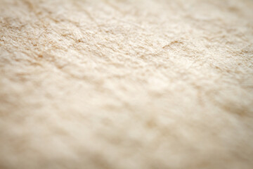 Extreme closeup of beige handmade paper with shallow depth of field.