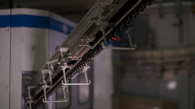 Preform bottles move along an automated conveyor system in a beverage production facility. These small plastic preforms will later be heated and expanded into full-sized bottles. The high-tech industr