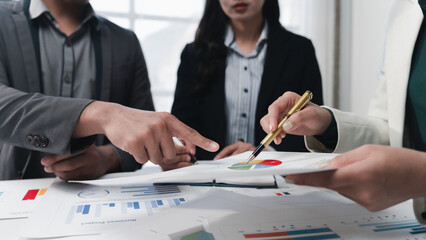 Business colleagues discussing financial data analyzing charts and graphs using pen and pointing at...