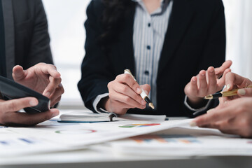 Corporate professionals reviewing financial documents, collaborating intensely around conference...