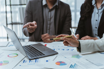 Professional team analyzing financial data, collaborating over laptop and documents in modern workplace setting