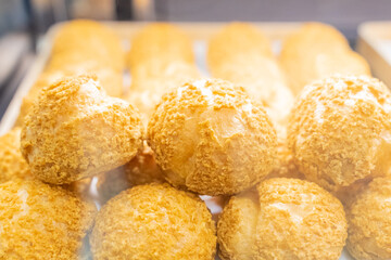 A beautifully designed restaurant communal space features sleek wooden benches positioned near a floor-to-ceiling glass facade, allowing natural light to flood the area. The warm tones of the wood