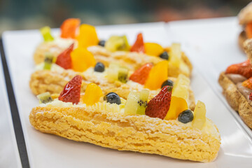 A beautifully designed restaurant communal space features sleek wooden benches positioned near a floor-to-ceiling glass facade, allowing natural light to flood the area. The warm tones of the wood