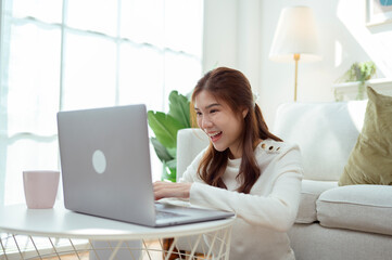 Naklejka premium Young Woman Enjoys Organizing Receipts While Using a Laptop in a Cozy Living Room During Daylight