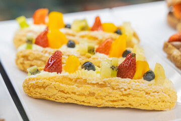 A beautifully designed restaurant communal space features sleek wooden benches positioned near a floor-to-ceiling glass facade, allowing natural light to flood the area. The warm tones of the wood