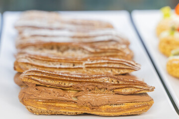 A beautifully designed restaurant communal space features sleek wooden benches positioned near a floor-to-ceiling glass facade, allowing natural light to flood the area. The warm tones of the wood