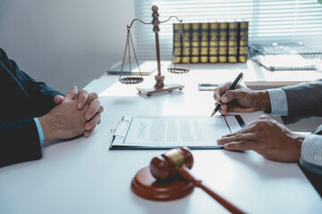 Legal professional signing settlement document beside law symbols in office setting