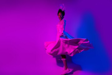 Vibrant portrait of a woman spinning in a luxurious gown under bold pink and blue neon lights
