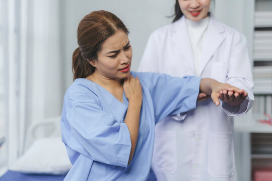 Medical professional palpating patient's shoulder, evaluating musculoskeletal discomfort during clinical examination in hospital setting