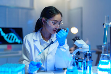 Fototapeta premium Scientist in lab coat and gloves using micropipette to drop liquid into test tube, with microscope and DNA structure on screen