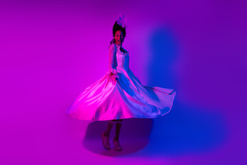 Elegant woman twirls gracefully in bright neon lights, wearing a white dress, evoking a sense of classic glamour and royalty