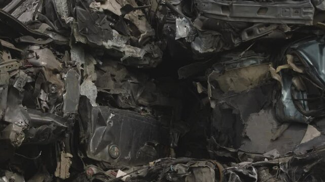 Pezzi di automobili demoliti e pressati da uno sfasciacarrozze