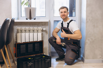 Plumber showing thumbs up near radiator and toolbox