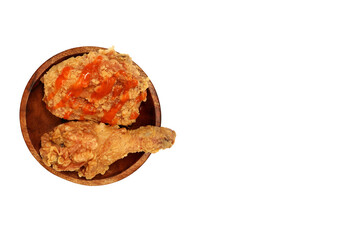 Fried chicken with sauce on top and served on a wooden plate, isolated on white background