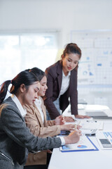 Asian businesswomen analyzing financial charts and graphs while working together in modern office
