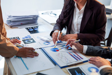 Business team analyzing financial charts and graphs using pens and pointing on data during a meeting