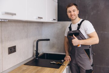 Plumber giving thumbs up after fixing kitchen faucet