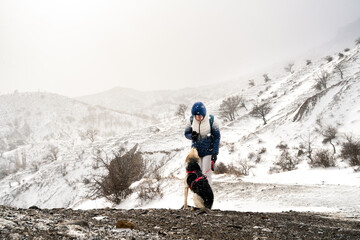 Dog and owner in winter nature. A young woman walks with her dog in the snowy mountains. The female...