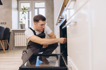 Plumber repairing oven in a modern kitchen